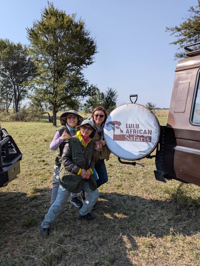 Lulu African Safaris guests beside a branded safari vehicle