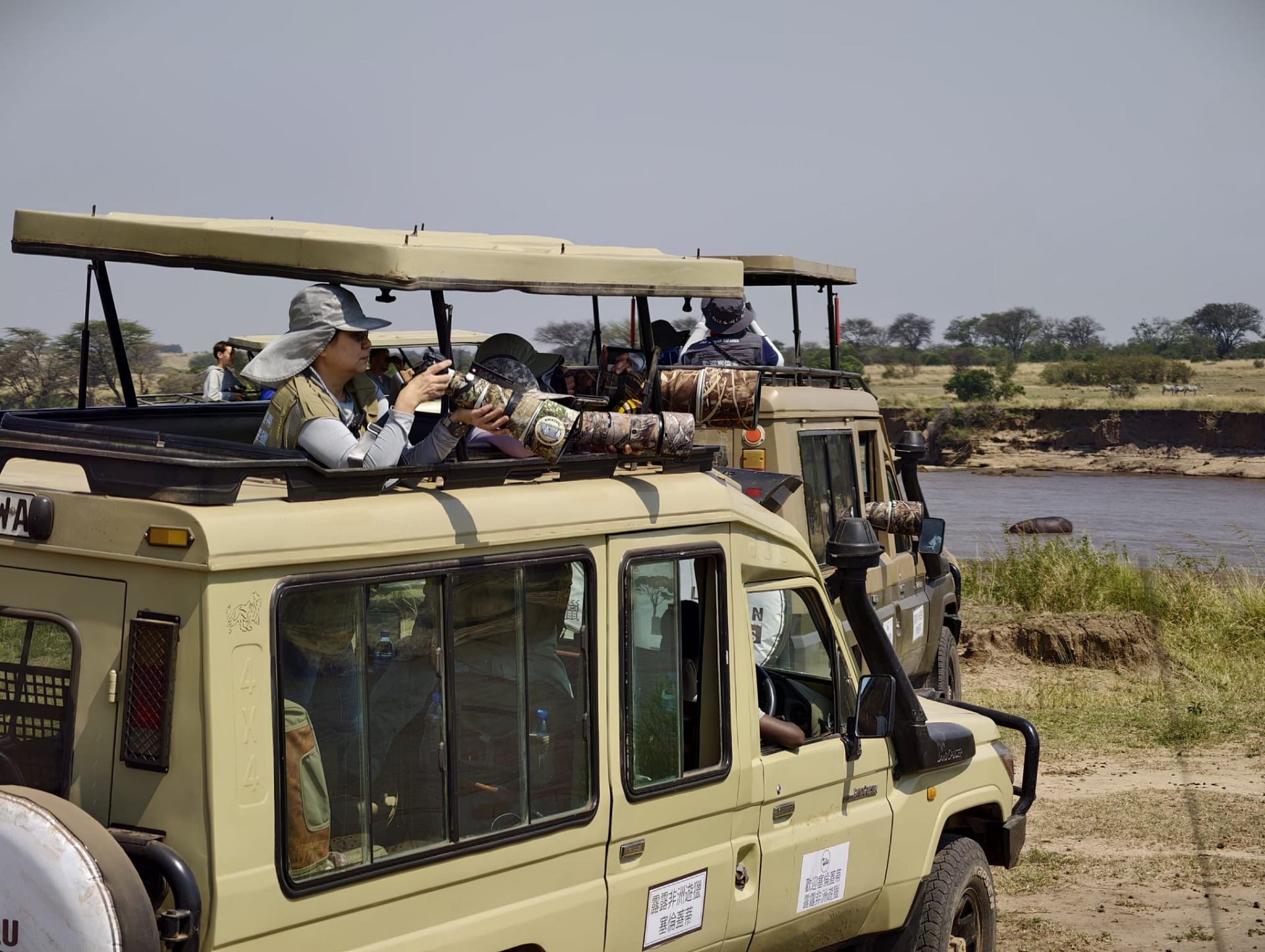 Guests photographing wildlife from a Lulu African Safaris Land Cruiser